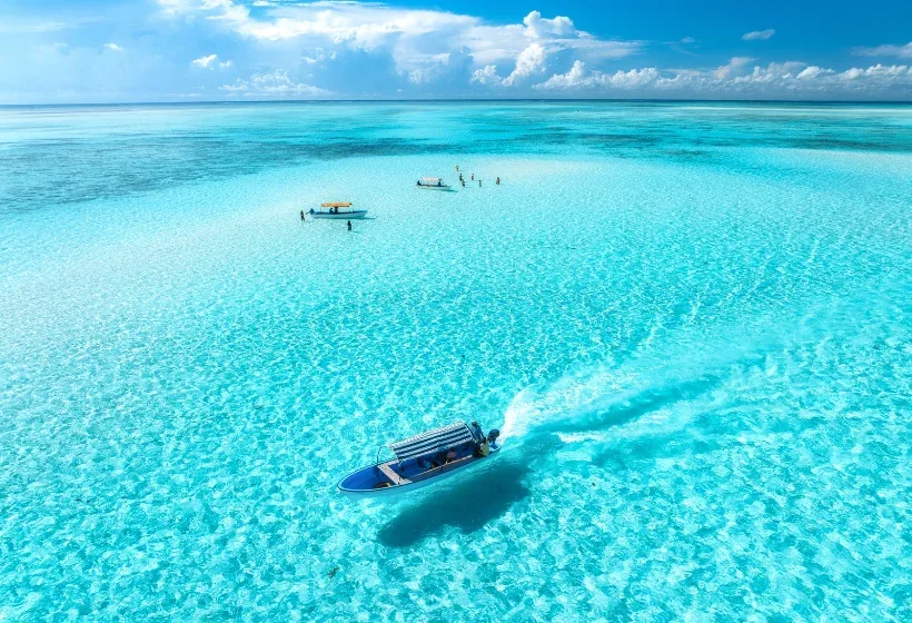 A boat drifting across a turquoise Zanzibar lagoon
